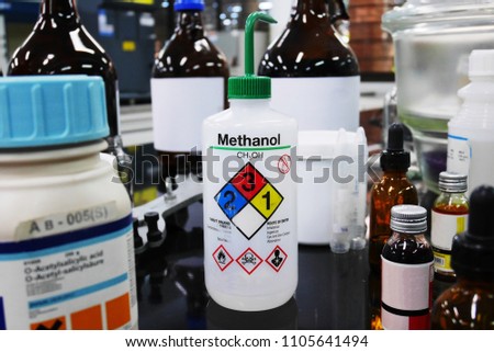 Bottle of Methanol and chemical with hazard warning symbols for experiment in Laboratory with Variety type of chemical container background.