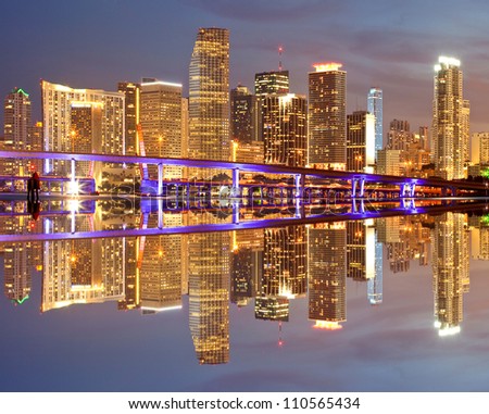 Miami Florida illuminated downtown buildings at night with reflections in the water of Biscayne Bay. Panoramic skyline of the World famous travel location