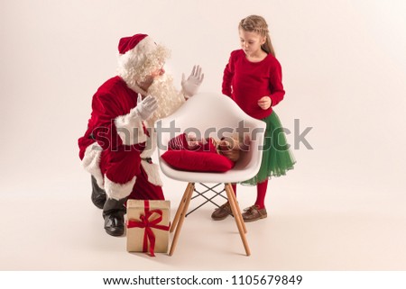 Christmas portrait of cute little newborn baby girl, pretty teen sister, dressed in christmas clothes and man wearing santa costume and hat, studio shot, winter time. The christmas, holidays concept