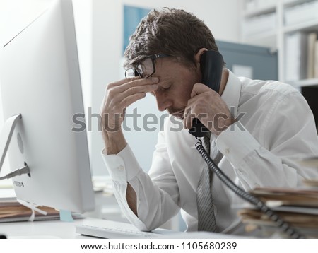 Business executive working in the office and receiving bad news on the phone, failure and crisis concept Royalty-Free Stock Photo #1105680239