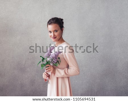 Woman with lilac brunch over gray background