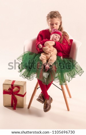 Happy little teen gir holding his newborn baby little sister at studio. Family love concept. The christmas, holidays concept
