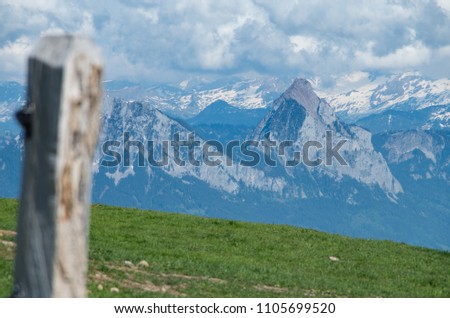 Grosser and Kleiner mythen as seen from mount rigi with a pole out of focus in the foreground over a green field