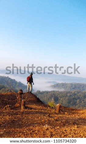 Tourists are standing in the mountains in front of the view of the mountain complex. Morning mist and nature make it fresh.