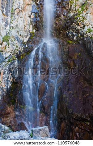 Picture of a waterfall, a few meters in height and moving through the stone mountain, Ala-Archa, Kyrgyzstan.