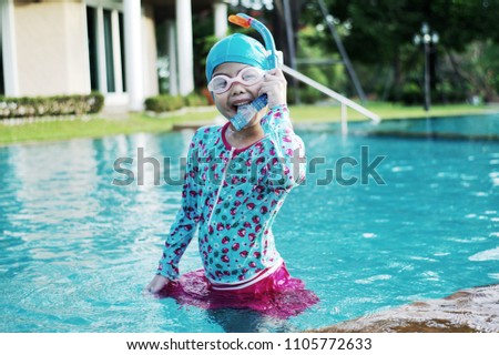 Portrait of asian girl holding the snorkel pipe and playing in the swimming pool. Girl enjoy swimming in the pool.