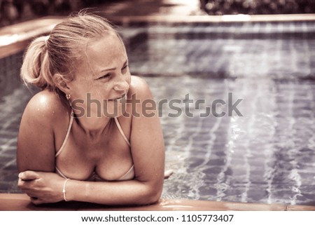 Beautiful woman relaxing in hotel  swimming pool looking at view in fashion style with copy space