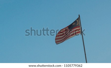 Malaysia national flag sky background at sunrise with golden light on flag