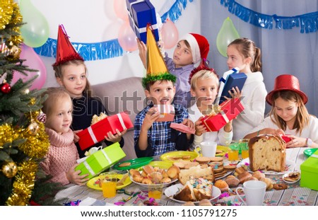 Boys and girls handing presents to each other during Christmas dinner in home