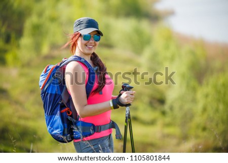 Image of sports girl with walking sticks on background of lake and green vegetation