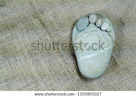 Tiny stone feet on sackcloth background