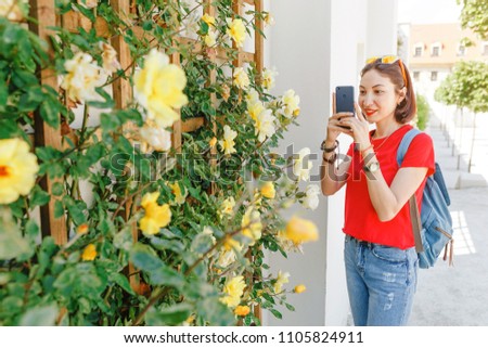 Girl instagram blogger takes pictures of flowers in the garden using her smartphone