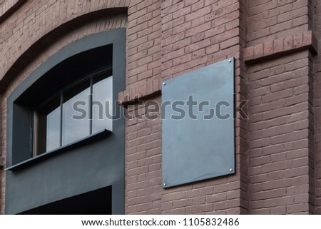 An empty plate on an old building of a dark brick factory. Mockup.