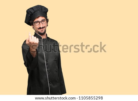 young crazy man as a chef smiling with a proud, satisfied and happy look, making a gesture as if accepting a challenge, confident of success.