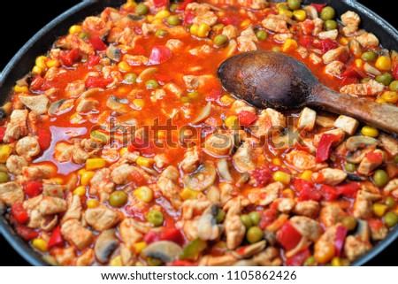 Homemade Mexican food as a background. Making of colorful tortilla stuffing on black pan. Freshly cooked fajita with wooden rustic spoon