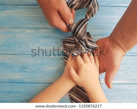 father's day hands dad and child tie against blue wooden background