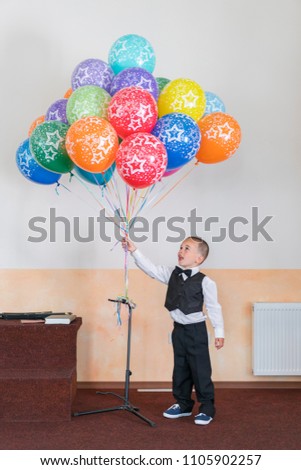 Boy 4 years holding colorful balloons. Happy boy on the stage holding balloons