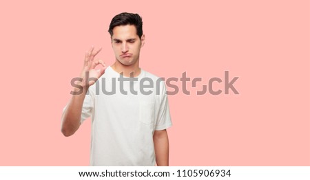 young handsome man making an "alright" or "okay" gesture approvingly with hand, looking happy and satisfied. Positive check sign.