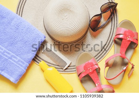 Sun straw hat, purple towel, yellow sunscreen bottle, sunglasses and red sandals. Flat lay photo beach essentials. Women's accessories for travel and summer rest