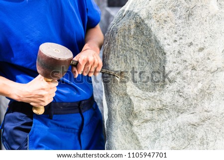 Stonemason working on boulder with sledgehammer and iron in workshop Royalty-Free Stock Photo #1105947701