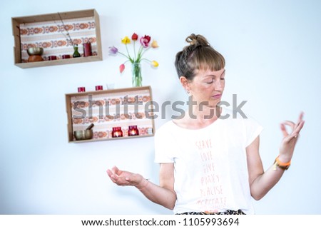 A female yoga teacher getting into balance. the blurred background shows shelves out of balance.