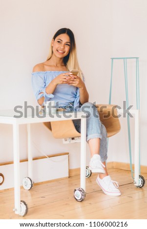 Young woman at cafe drinking coffee and using mobile phone
