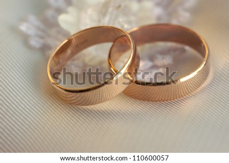 Two wedding rings lie on a white pillow