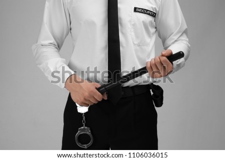 Male security guard with police baton on color background