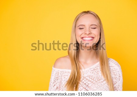 Portrait with copy space empty place of comic funky girl laughing with clenched teeth keeping eyes closed isolated on yellow background