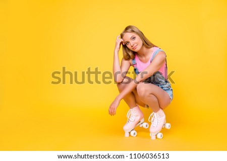 Portrait with copyspace empty place of pretty gorgeous girl on roller skates sitting looking at camera isolated on yellow background