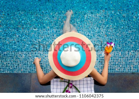 Asian woman in bikini relaxing on the pool in sunny day,Summer holiday idyllic,enjoy and relax happiness emotion for life comfortable in fruit punch in swimming pool;vacation concept.
