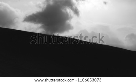 Small skier on big cloudy mountain black and white Royalty-Free Stock Photo #1106053073