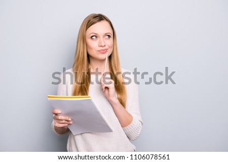 Portrait with copy space empty place of thoughtful pensive girl having copybook and pen in hands looking up, writer waiting for muse, isolated on grey background Royalty-Free Stock Photo #1106078561