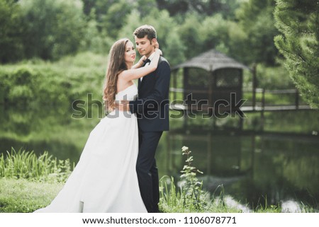 Stylish couple of happy newlyweds posing in the park on their wedding day