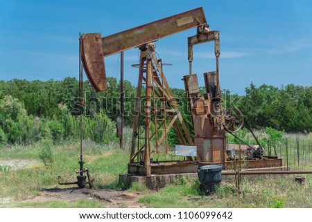 Close-up working pump jack fracking crude extraction machine. Pumping crude oil out of well to tank. Pumper, water emulsion at oil drilling site in Gainesville, TX, US. Energy, Industrial background Royalty-Free Stock Photo #1106099642