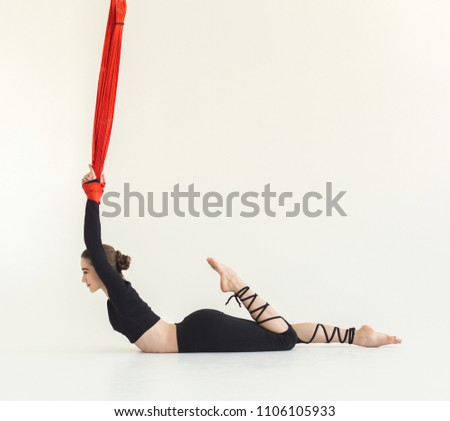 Sporty woman practicing fly yoga asana and stretching over white background in fitness gym, copy space. Health, sport, yoga concept