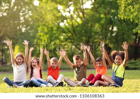 Cute little children sitting on grass outdoors on sunny day