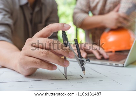 Hands of architect or engineer using drawing compass with blueprint on desk in office.Team of architects engineer discussing and check documents and business workflow.Construction concept.