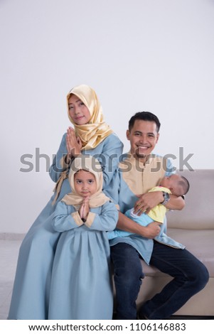 happy young asian muslim family while sitting on a couch