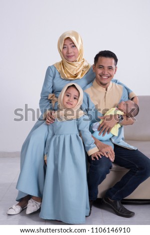 portrait of beautiful muslim family with kids sitting on a couch over white background