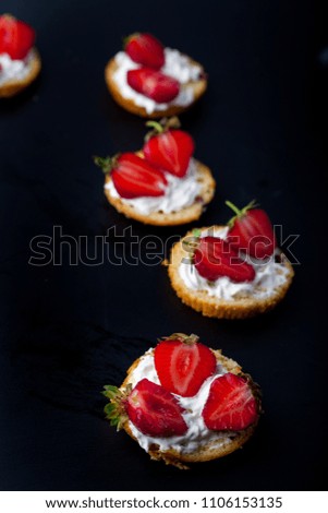Fluffy buttermilk biscuits shortcake with red ripe strawberries and fresh whipped cream on a black background