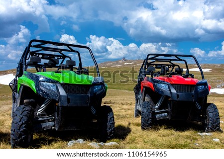 Parked ATV and UTV, buggies on mountain peak with clouds and blue sky in background Royalty-Free Stock Photo #1106154965