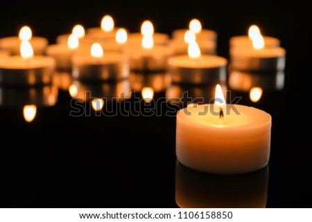 Wax candle burning on table in darkness, closeup