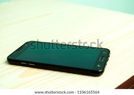Black mobile phone with padlock and key isolated on wodden background