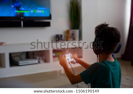 Back view of concentrated young gamer playing game. gaming game play tv fun gamer gamepad guy controller video console playing player holding hobby playful enjoyment view concept.
