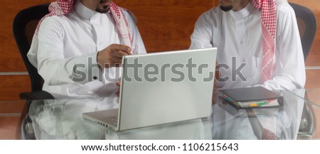 Two Saudi Businessmen Meeting, Working on a Laptop Royalty-Free Stock Photo #1106215643