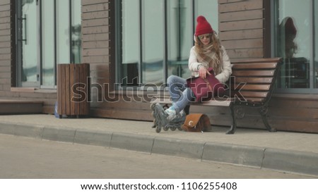 Young beautiful woman in a red hat, wearing sporty warm clothes and rollers, riding on the road on the coast 4k
