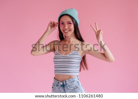 Young asian teenage girl in shorts and pink sunglasses isolated on pink background.