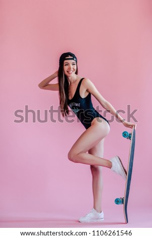 Young asian teenage girl on pink background. Young woman in swimsuit with skateboard isolated.