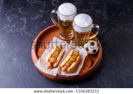Photo on top of two glasses of beer and hot dogs on wooden tray with football